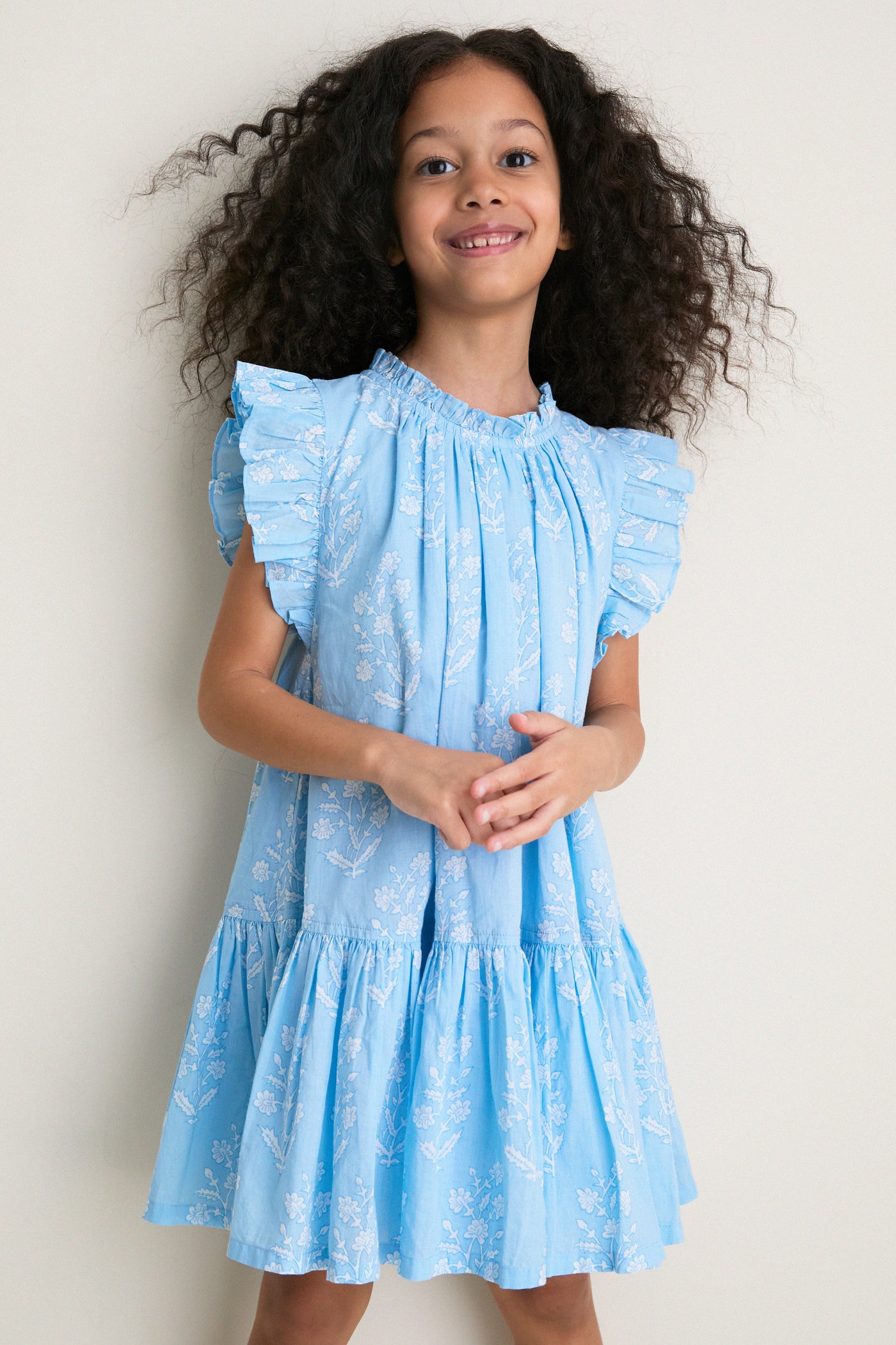 Young girl wearing the Blue Dewdrop Blockprint Harper Dress: a classic, effortless, high-end cotton dress with ruffle sleeves, capturing fun and comfort.