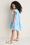 Young girl in profile wearing the classic Blue Dewdrop Block Print Harper Dress, showcasing effortless charm with ruffled sleeves and a fun, high-end flouncy silhouette.