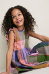 Young girl in Plaid Madras Alyssa Dress, featuring playful ruffles and silver buttons, exudes effortless, fun style, embodying classic, high-end charm.