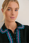 Young woman wears the Deep Black Multi Polo Sweater with classic ric-rac trim, showcasing a sophisticated yet effortless style, perfect for a fun, high-end look.