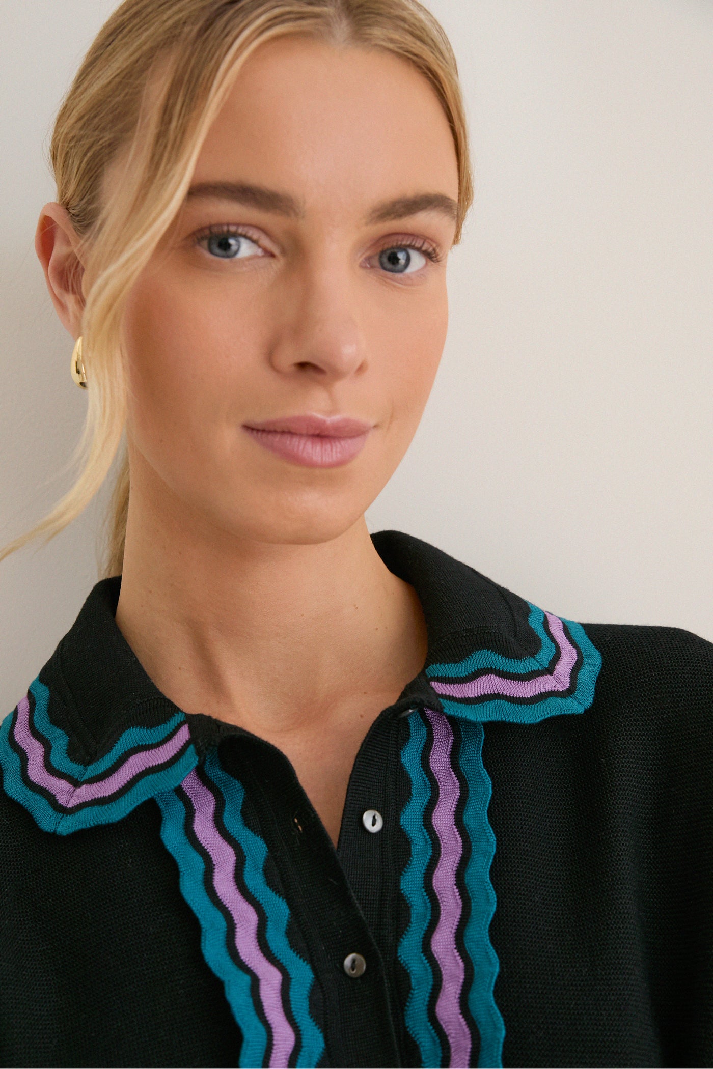 Young woman wears the Deep Black Multi Polo Sweater with classic ric-rac trim, showcasing a sophisticated yet effortless style, perfect for a fun, high-end look.