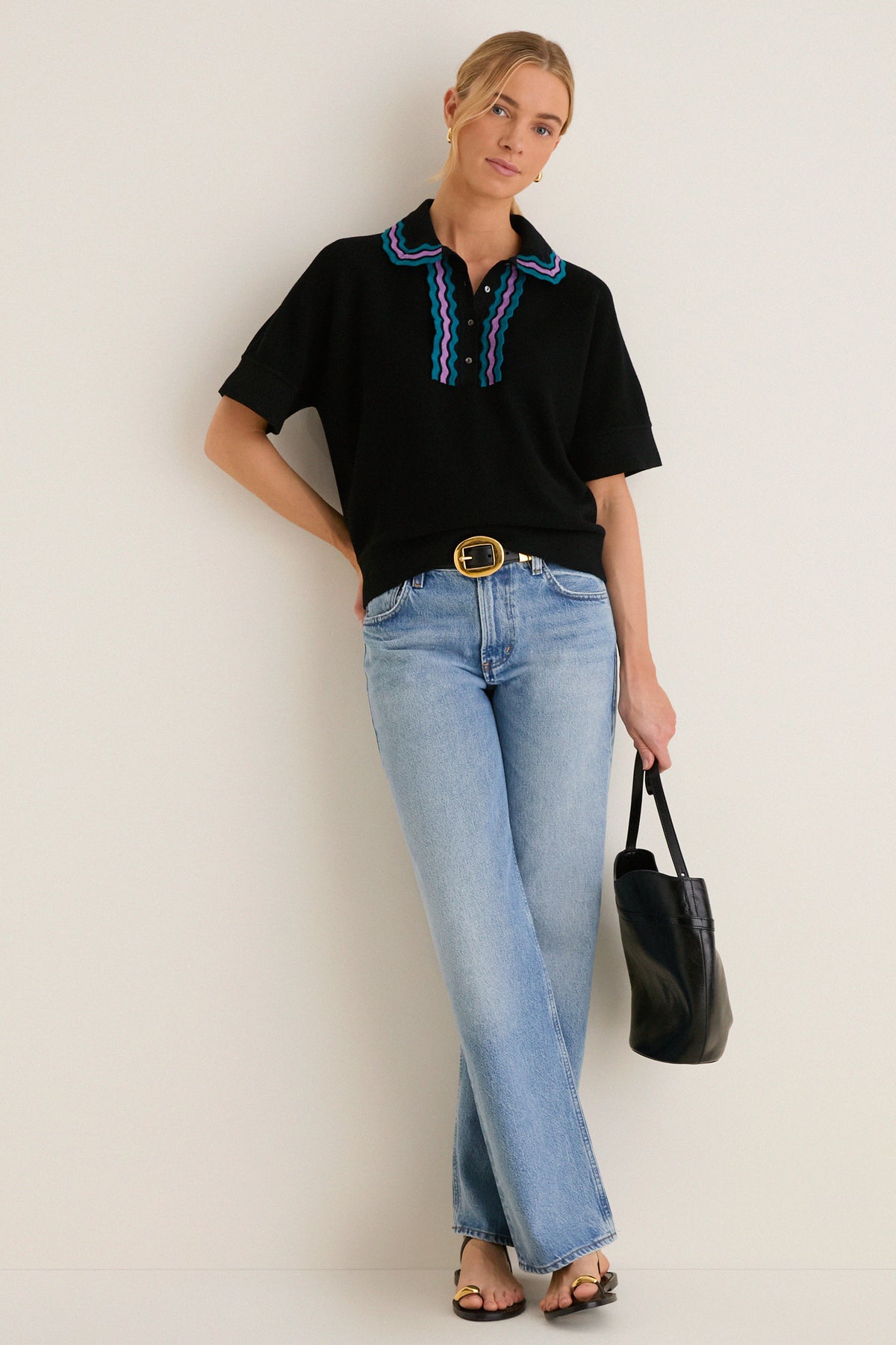 Young woman wearing the Deep Black Multi Polo Sweater with ric-rac trim, paired with light-wash jeans and black accessories, embodying a classic yet effortless high-end style.