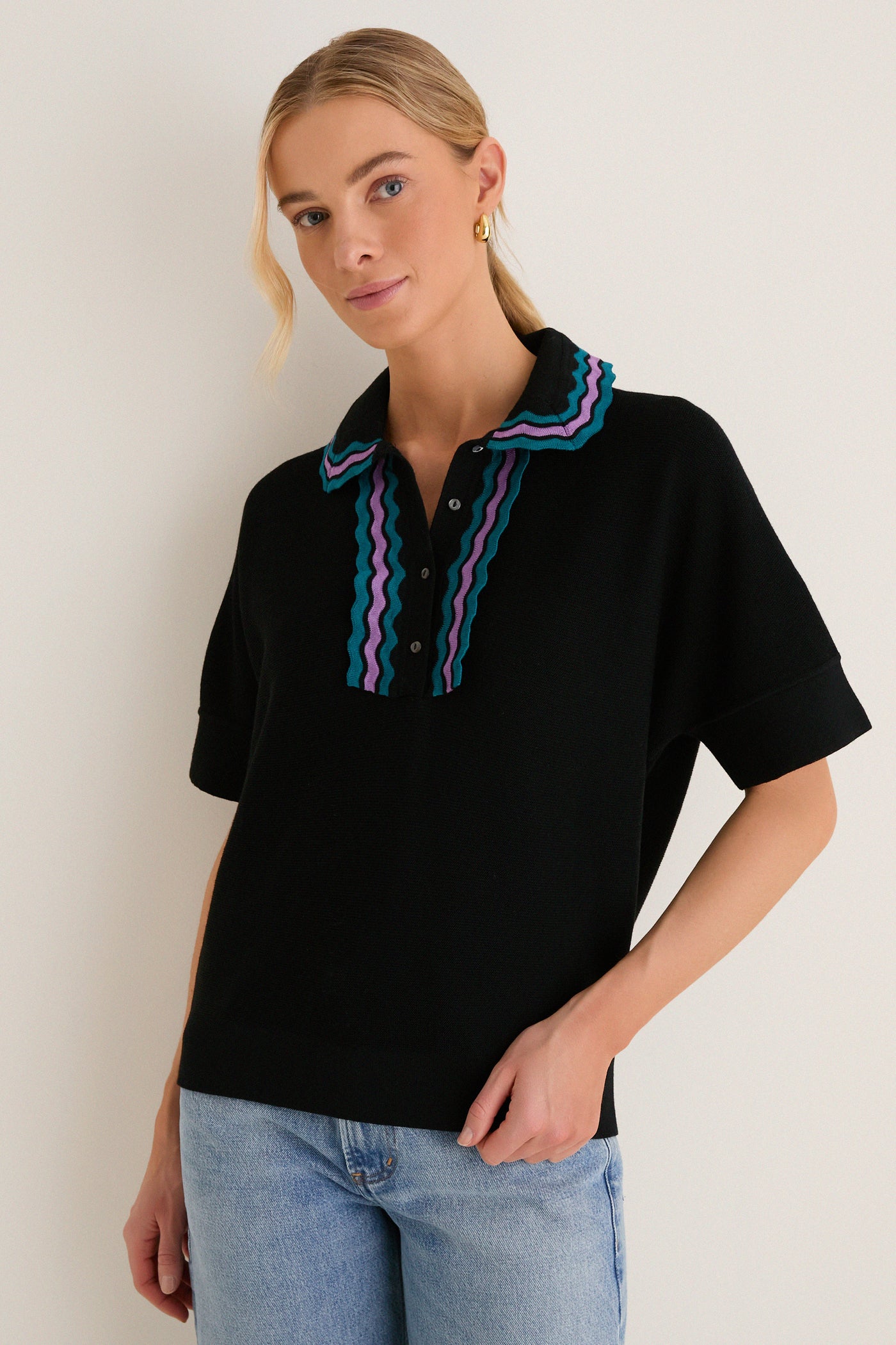 Woman in a classic, effortless Deep Black Multi Polo Sweater with playful teal and purple ric-rac details, paired with light-wash jeans, exuding a high-end, fun vibe.