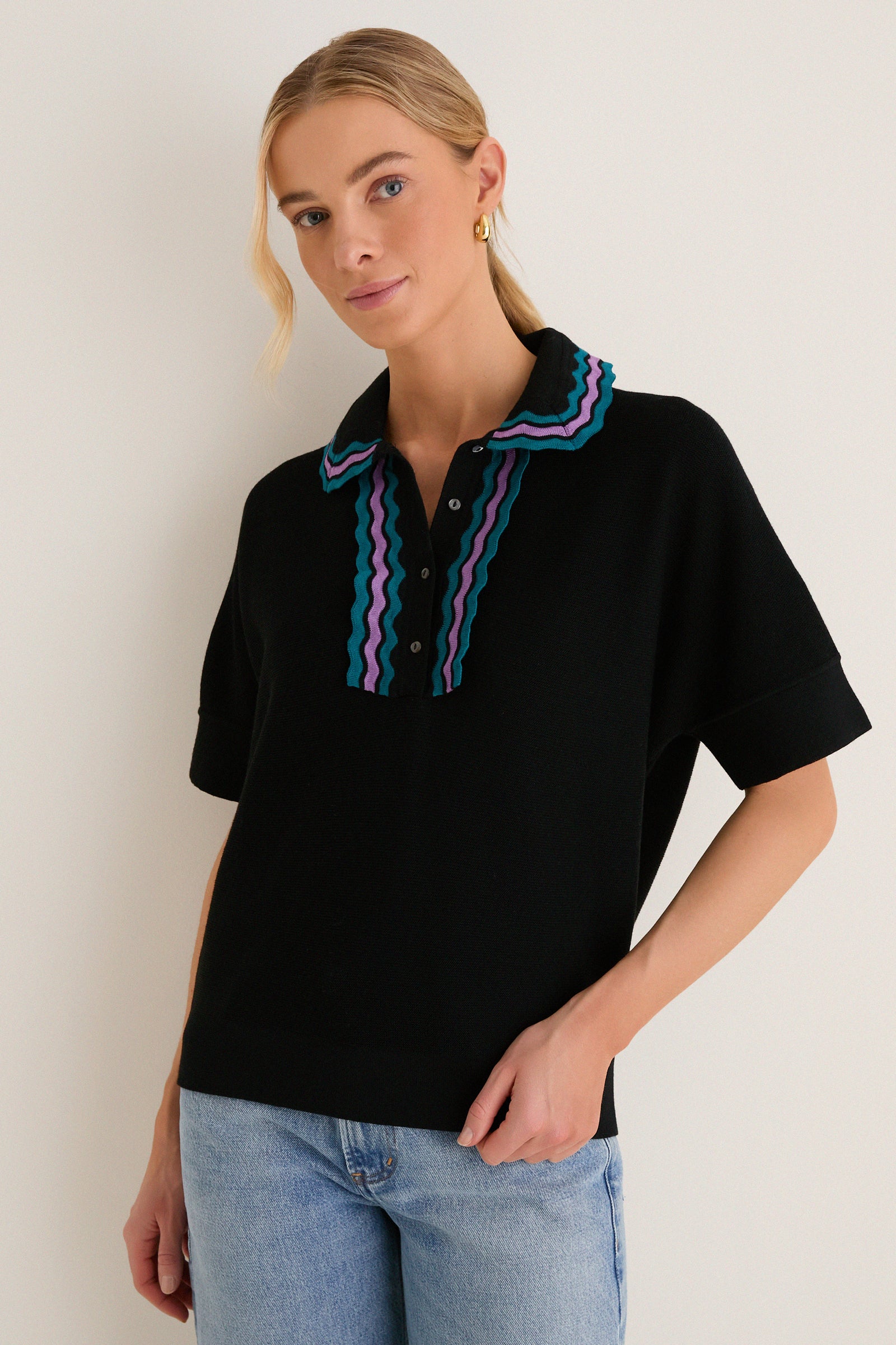 Woman in a classic, effortless Deep Black Multi Polo Sweater with playful teal and purple ric-rac details, paired with light-wash jeans, exuding a high-end, fun vibe.