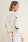 Woman in a classic Milk Multi Dump Sweater with pastel embroidery, paired with a matching skirt. Effortless, fun, high-end look for spring.