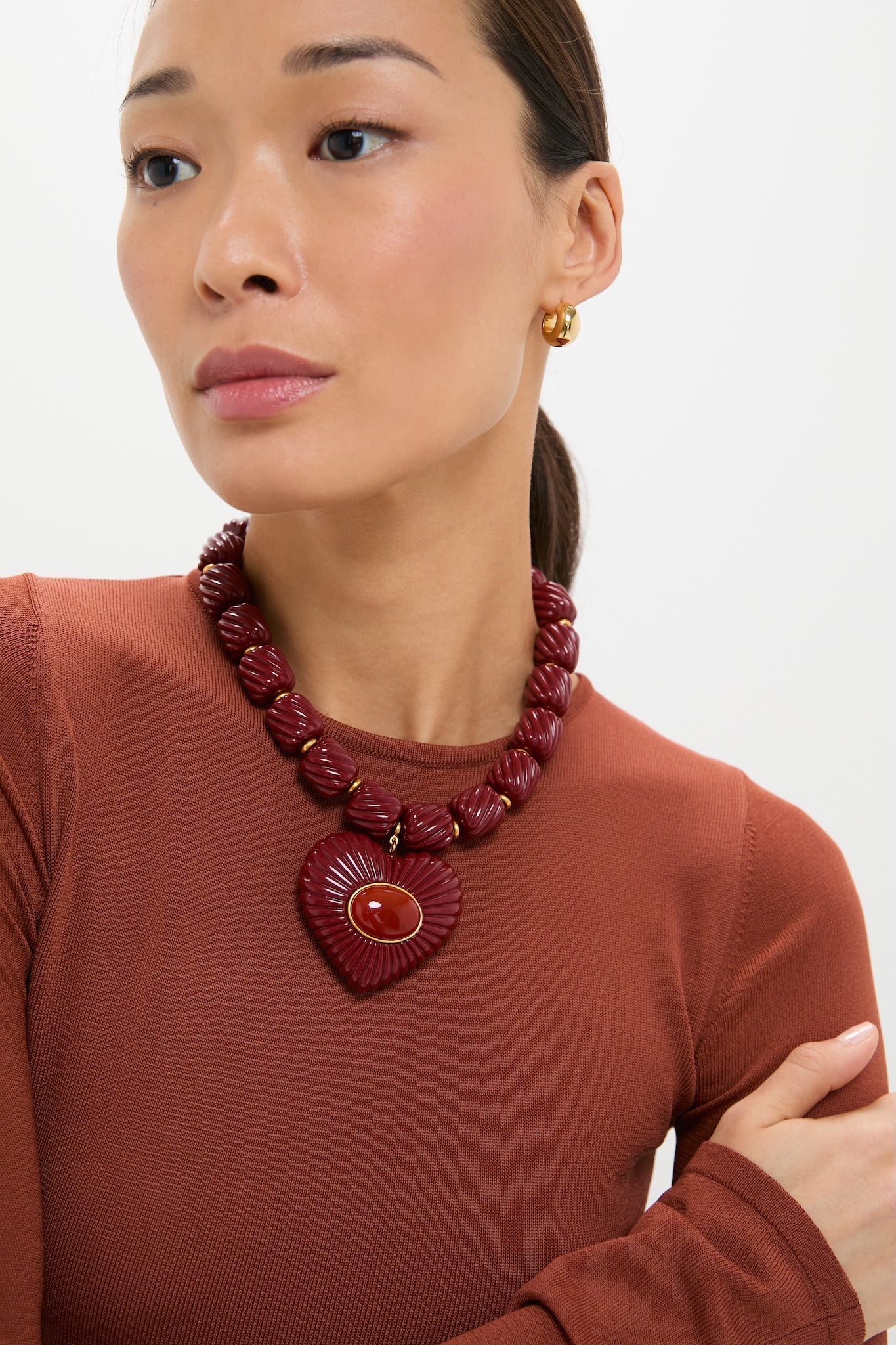 Woman wearing the Burgundy Lira Necklace with a striking heart pendant and magnetic clasp, embodying effortless, high-end style. Perfect for adding a classic, fun touch.