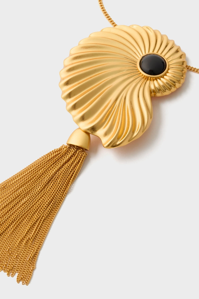 Gold Aveline Necklace: A classic gold-tone pendant featuring a stylized seashell with a central black stone and a tassel of fine chains, offering an effortless, high-end look.