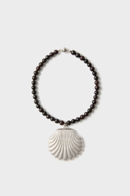 Silver Holbox Necklace: A classic, high-end piece featuring dark beads and a bold silver scallop-shell pendant, effortlessly elevating any look with fun sophistication.
