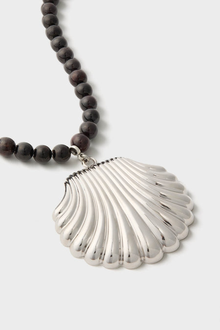 Silver Holbox Necklace: A classic, high-end design featuring dark beads and an oversized shell-shaped pendant, effortlessly elevating any look with fun sophistication.