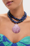 Navy and Lilac Luma Necklace: A classic, high-end two-strand necklace of chunky dark blue beads with a scallop shell pendant, creating an effortless, fun style.