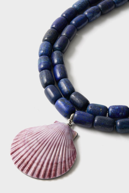 Navy and Lilac Luma Necklace featuring chunky blue beads and a scallop shell pendant, exuding a classic and effortlessly cool high-end style.