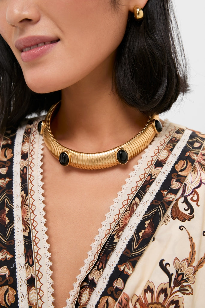 A classic Gold Celeste Necklace with black stone cabochons offers an effortless, high-end look, paired with polished gold drop earrings for a fun, sophisticated style.