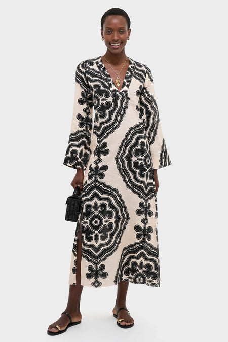 Woman models a classic, long V-neck dress with abstract pattern, highlighting the Gold Buona Fortuna Necklace's effortless charm and fun, high-end appeal.