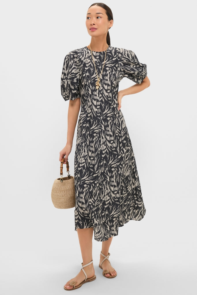 Woman in a classic, effortless mid-length dress with a woven straw bag, layered gold necklaces, including the high-end Gold The Family of Hearts Pendant.