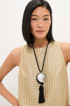 Young woman wearing the Black Nautilus Necklace, featuring a classic shell-inspired pendant and tassel, exuding effortless elegance and high-end style.