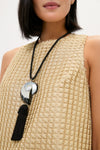 Woman wearing a classic Black Nautilus Necklace featuring an iridescent shell pendant and a chunky black tassel, creating an effortless and high-end look.