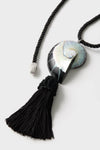 Black Nautilus Necklace features a classic spiral shell-like pendant on a twisted cord with tassel, blending effortless elegance with a fun, high-end design.