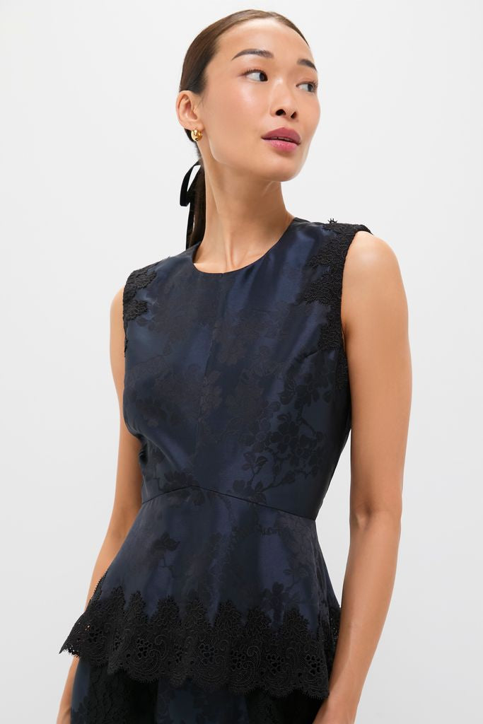Woman wearing the classic Navy and Black Lace Margy Top, featuring an effortless peplum design with fun lace details, exuding a high-end, versatile style.
