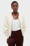 Ivory Sequin Trim Naomi Cardigan on a woman, paired with a white V-neck top and burgundy trousers, showcasing a classic, effortless, and high-end style.