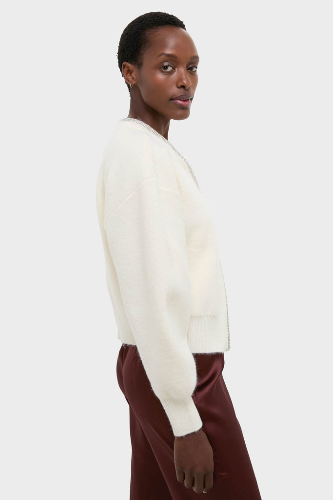 Person wearing the Ivory Sequin Trim Naomi Cardigan, a classic, oversized knit sweater paired with burgundy pants, exuding an effortless, high-end style.