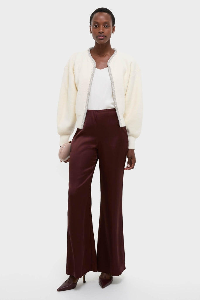 Model wearing the classic Ivory Sequin Trim Naomi Cardigan with metallic accents, paired with burgundy trousers, embodying an effortless, high-end style with a fun, modern twist.