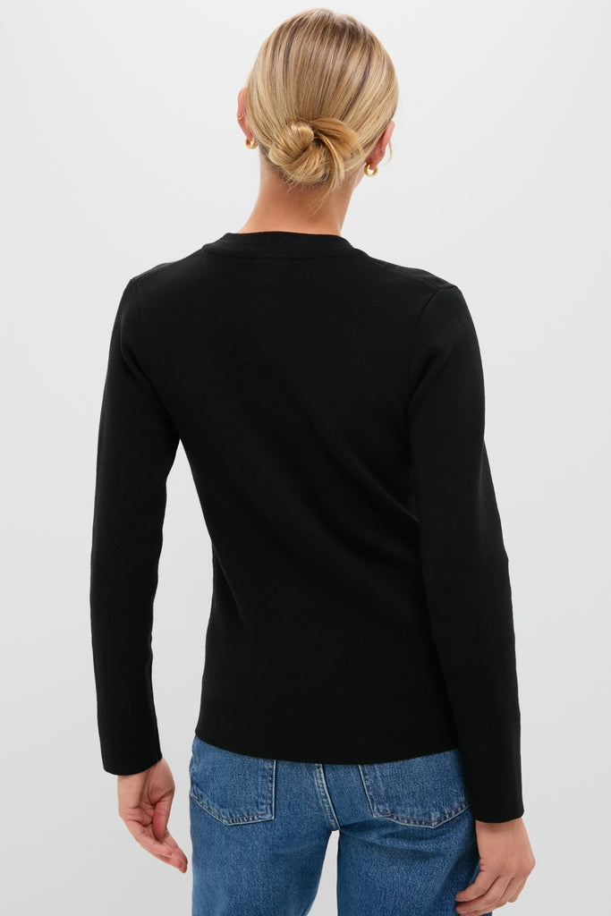 Back view of person in classic Black Viscose Margaux Cardigan, paired with medium-wash jeans, exuding an effortless, high-end style with fun, small gold hoop earrings.