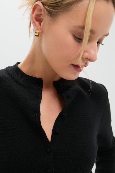 Woman wearing a classic Black Viscose Margaux Cardigan with effortless style, featuring undone buttons and high-end stacked gold hoop earrings, embodying Tuckernuck’s fun and cool aesthetic.