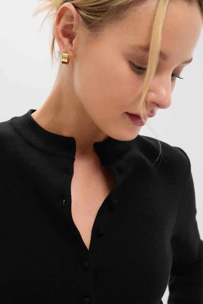Woman wearing a classic Black Viscose Margaux Cardigan with effortless style, featuring undone buttons and high-end stacked gold hoop earrings, embodying Tuckernuck’s fun and cool aesthetic.