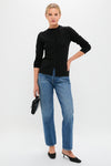 Woman in Black Viscose Margaux Cardigan, exuding classic elegance and effortless style, paired with straight-leg jeans and slingback shoes, holding a chic black handbag.
