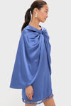 Model in profile showcasing the Blue Satin Mountbatten Cape, effortlessly draped over a matching mini dress with tassel hem, exuding classic, high-end style perfect for fun, festive occasions.