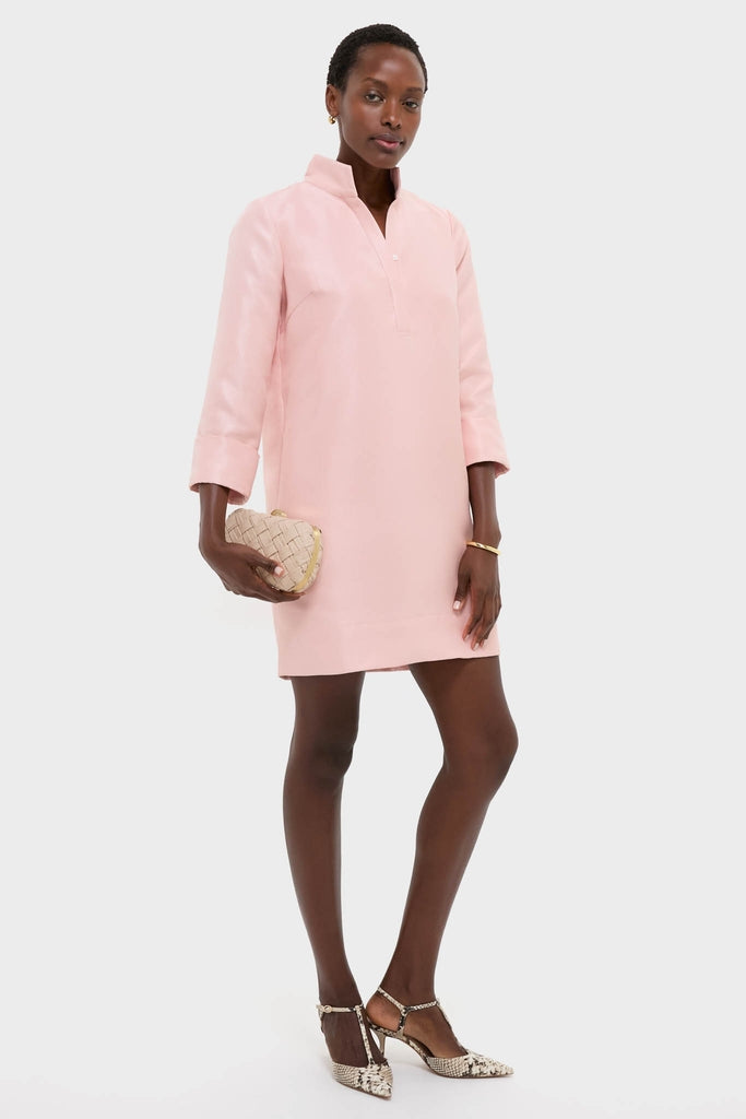 Model in a classic, effortless Soft Pink Dupioni Megan Dress with three-quarter sleeves, holding a woven clutch and wearing T-strap heels, embodying a fun, high-end style.