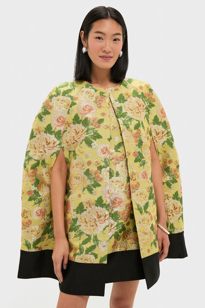 Fashion model wearing the Chrysanthemum Jacquard Noel Cape, a classic, effortless piece with dramatic floral jacquard and contrast trim, embodying high-end, fun style with silver accessories.