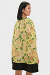 Woman in profile wearing the classic Chrysanthemum Jacquard Noel Cape, an effortlessly fun and high-end floral piece, over a simple black dress.