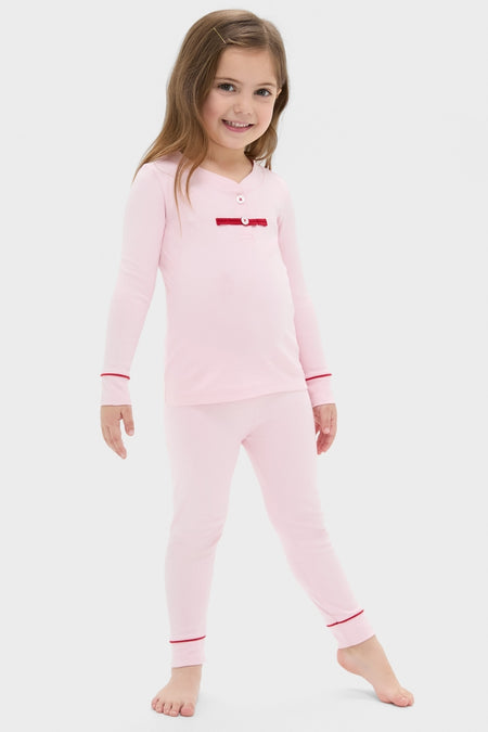 Young girl smiling in Pink Arien Kid's Pajama Set, featuring a mandarin collar, red-trim details, and a ribbon accent, embodying classic, effortless comfort and high-end style.