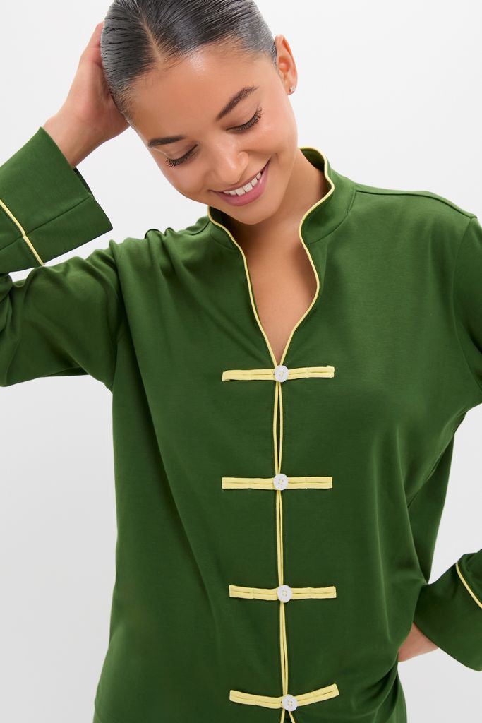 Woman wearing the classic Green Wilford Women's Pajama Set, featuring an effortless mandarin collar and frog-toggle closures, smiling softly, embodying Tuckernuck's fun, high-end style.