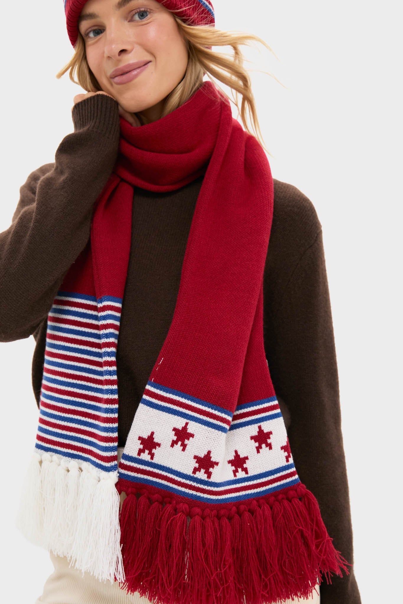 Person in dark sweater wears the USA Salt Lake Scarf, featuring classic stars, stripes, and tassel detailing, paired with a matching beanie for an effortless, high-end winter look.