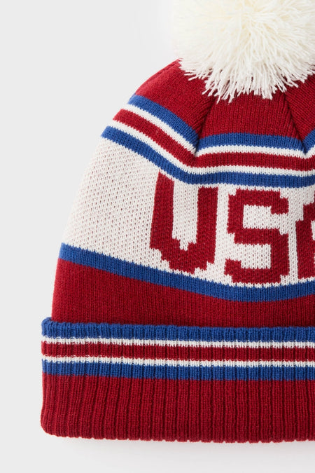 USA Telluride Hat: A classic, effortlessly fun beanie with red, white, and blue stripes, USA letters, and a fluffy pom-pom for high-end winter style.