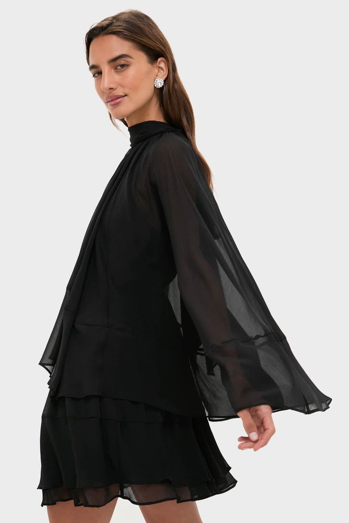 Model wearing the classic Black Cape Chiffon Mayfield Dress, featuring an effortless high neckline, fun bell sleeves, and a tiered skirt, exuding a high-end, chic vibe.