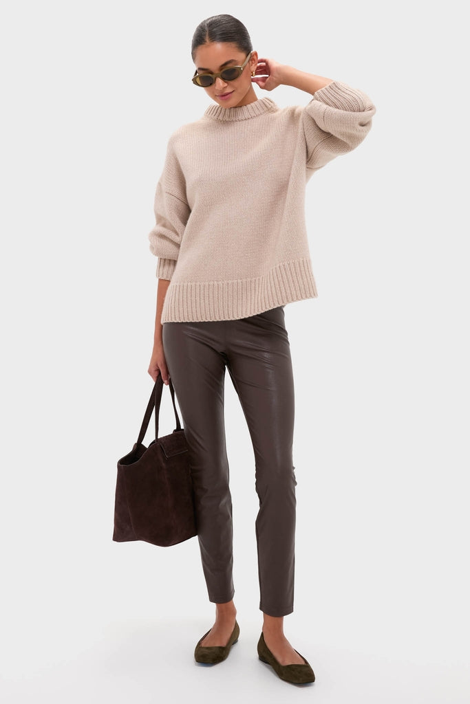 Woman wearing Shiny Solid Licorice Brown Corner Angle M Sunglasses with oval shape, showcasing a classic, effortless style paired with slim dark pants and a loose beige sweater.