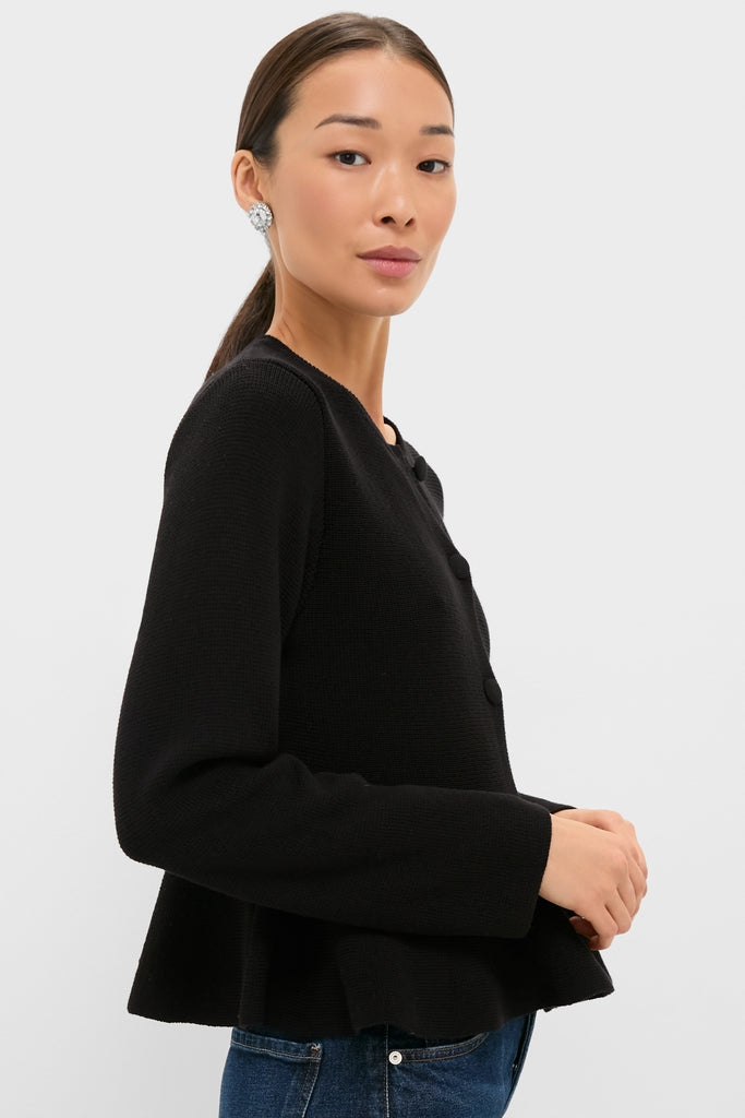 Side view of a model in a Black Knit Richmond Sweater with covered buttons and blue jeans, showcasing a classic, effortless style with a fun, high-end flair.