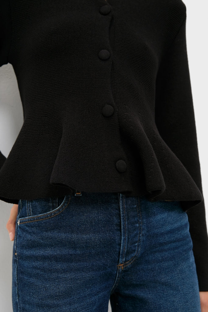 Black Knit Richmond Sweater with fabric-covered buttons and a peplum flare, paired with blue jeans, showcasing an effortless, classic, and high-end look.