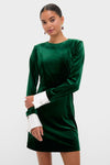 Hunter Green Velvet Etta Mini Dress modeled against a light background, showcasing its classic, high-end design with effortless style, featuring removable white cuffs and drop earrings.