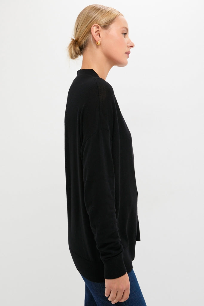 Black Cross Button Calloway Cardigan in a classic, effortless style, featuring an asymmetrical button placket and side cinch, worn with jeans for a high-end, fun look.