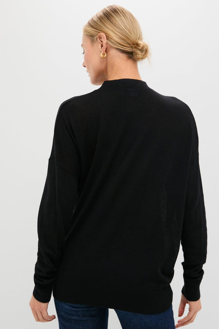 Person wearing the Black Cross Button Calloway Cardigan with asymmetrical buttons and side cinch, styled with jeans for a classic, effortless, and high-end look.