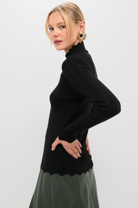 Young woman models the Black Pointelle Knit Allen Turtleneck with scalloped trim, exuding classic, effortless style. Perfectly paired with an olive skirt for a high-end, fun look.