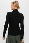Model in a Black Pointelle Knit Allen Turtleneck with scalloped hem, styled effortlessly with a high-waisted olive skirt, embodying classic, high-end fashion.
