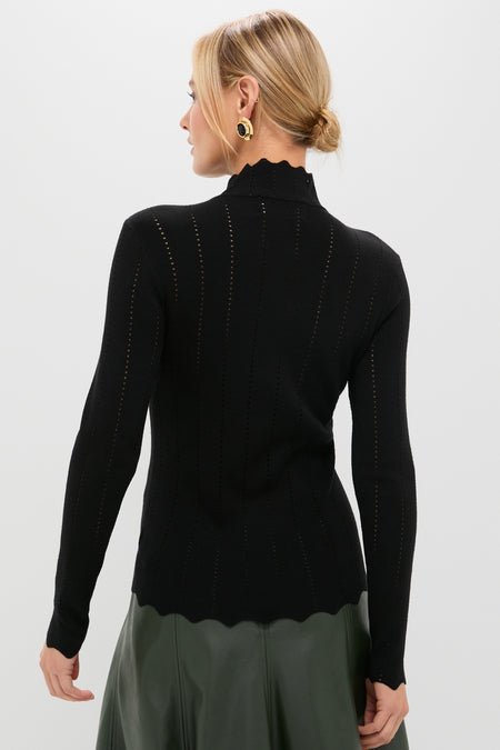 Model in a Black Pointelle Knit Allen Turtleneck with scalloped hem, styled effortlessly with a high-waisted olive skirt, embodying classic, high-end fashion.