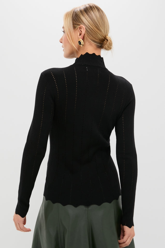 Model in a Black Pointelle Knit Allen Turtleneck with scalloped hem, styled effortlessly with a high-waisted olive skirt, embodying classic, high-end fashion.
