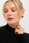 Woman in a Black Pointelle Knit Allen Turtleneck with scalloped mock-neck and statement hoop earring, embodying classic, effortless style.