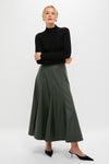 Woman models Black Pointelle Knit Allen Turtleneck with scalloped neck, paired with a high-waisted flared skirt and mules, showcasing an effortlessly classic and high-end look.